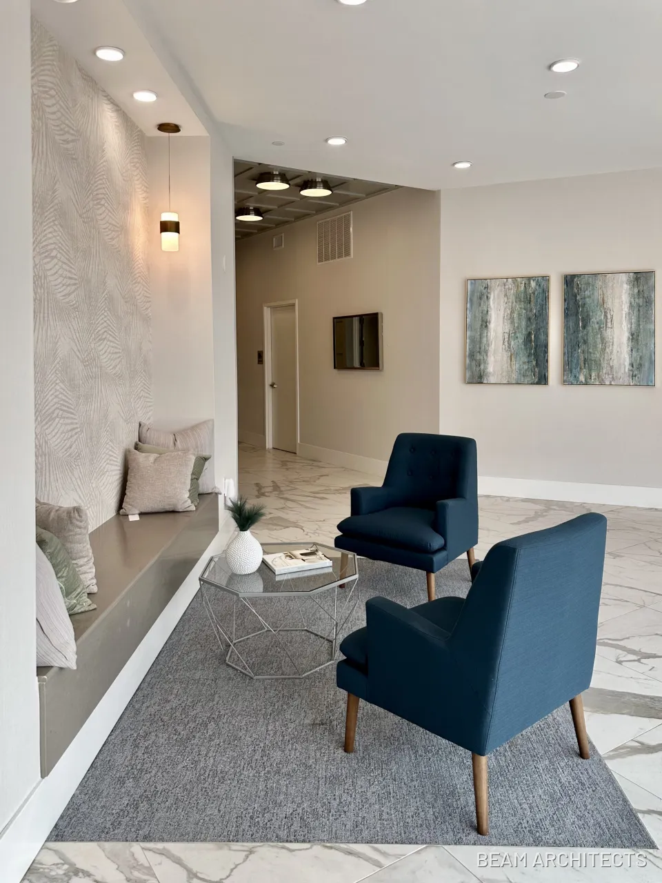 Completed lobby at 110 Washington with two blue armchairs, a built-in bench and artwork.